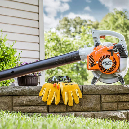 Stihl leaf blower on a stone ledge with yellow gloves and sunglasses, outdoor setting.