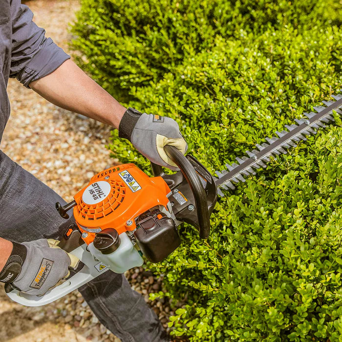 Person using a hedge trimmer to trim a bush